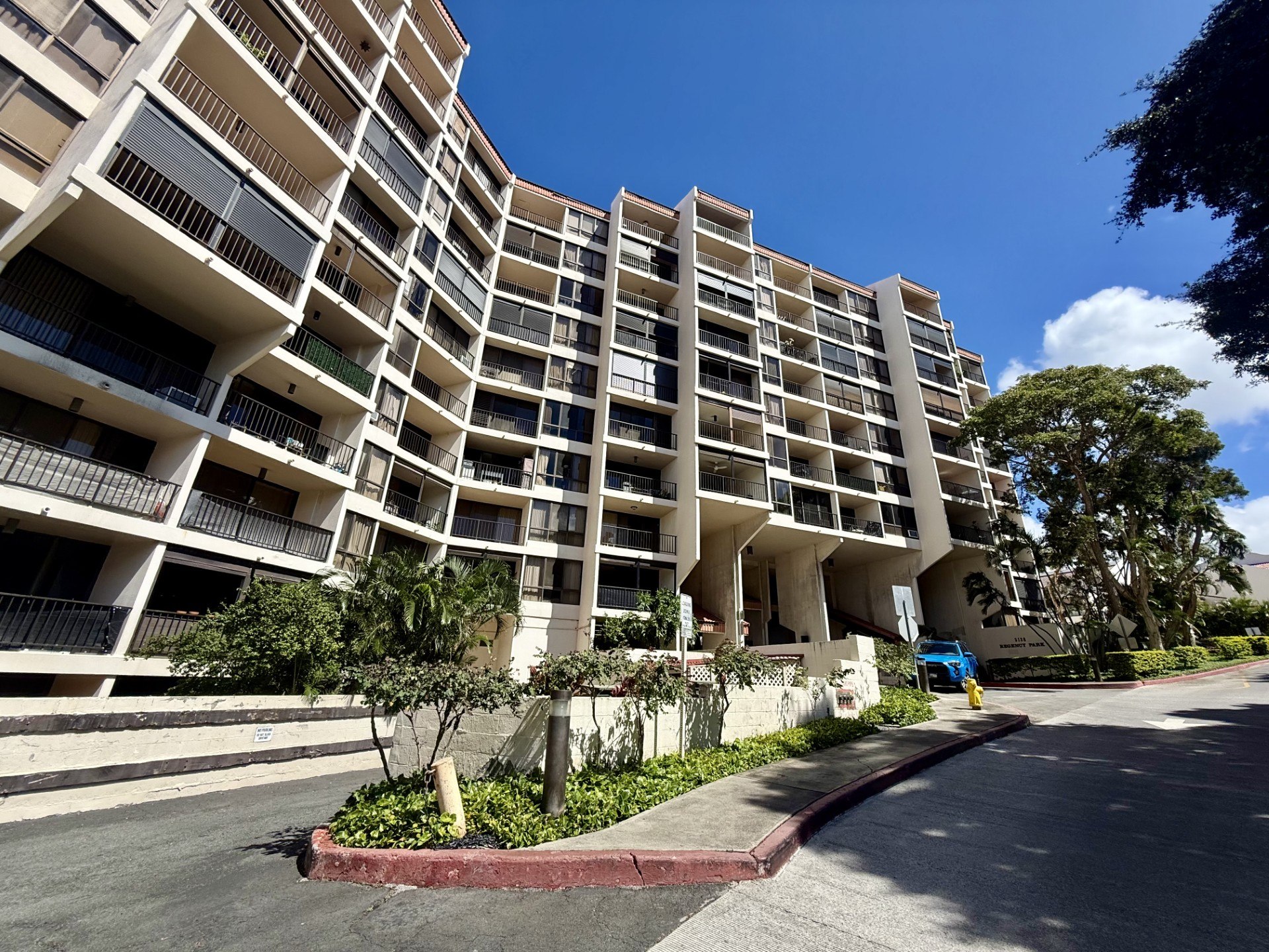 A large apartment complex with multiple balconies and a clear blue sky above.